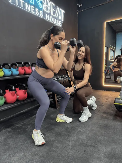 מאמנת מלווה מתאמנת בסקוואט עם משקולת